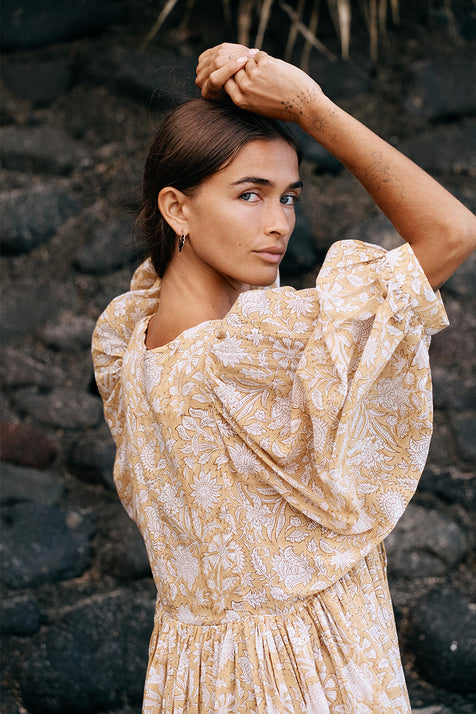 Daughters of India Kyra Midi Dress in Cumin — back close-up by volcanic rocks, billowed sleeves, cumin floral print