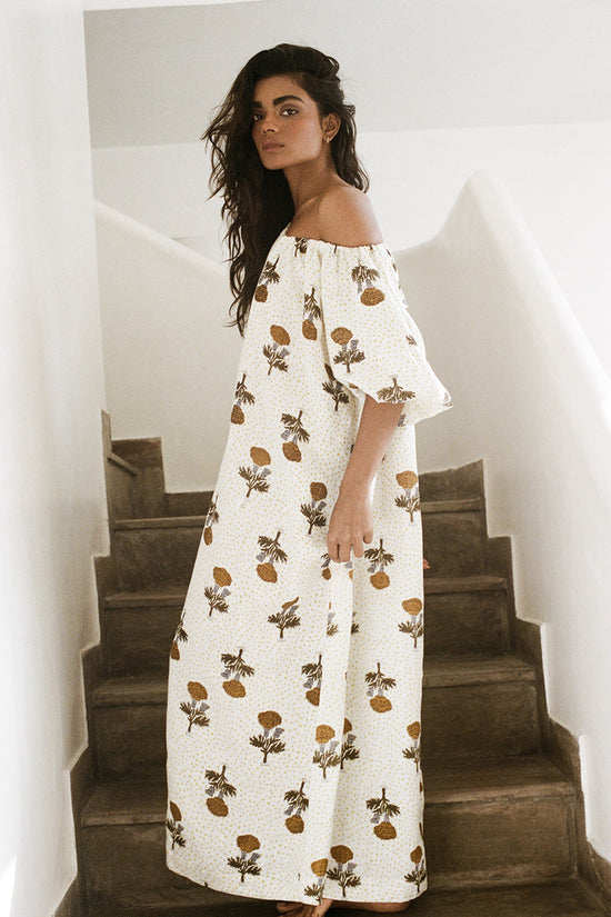 Dahlia Maxi Dress Marigold — full length on stone staircase side view, off-shoulder, white linen with golden marigold Jaipur block print, ethical slow fashion | Daughters of India
